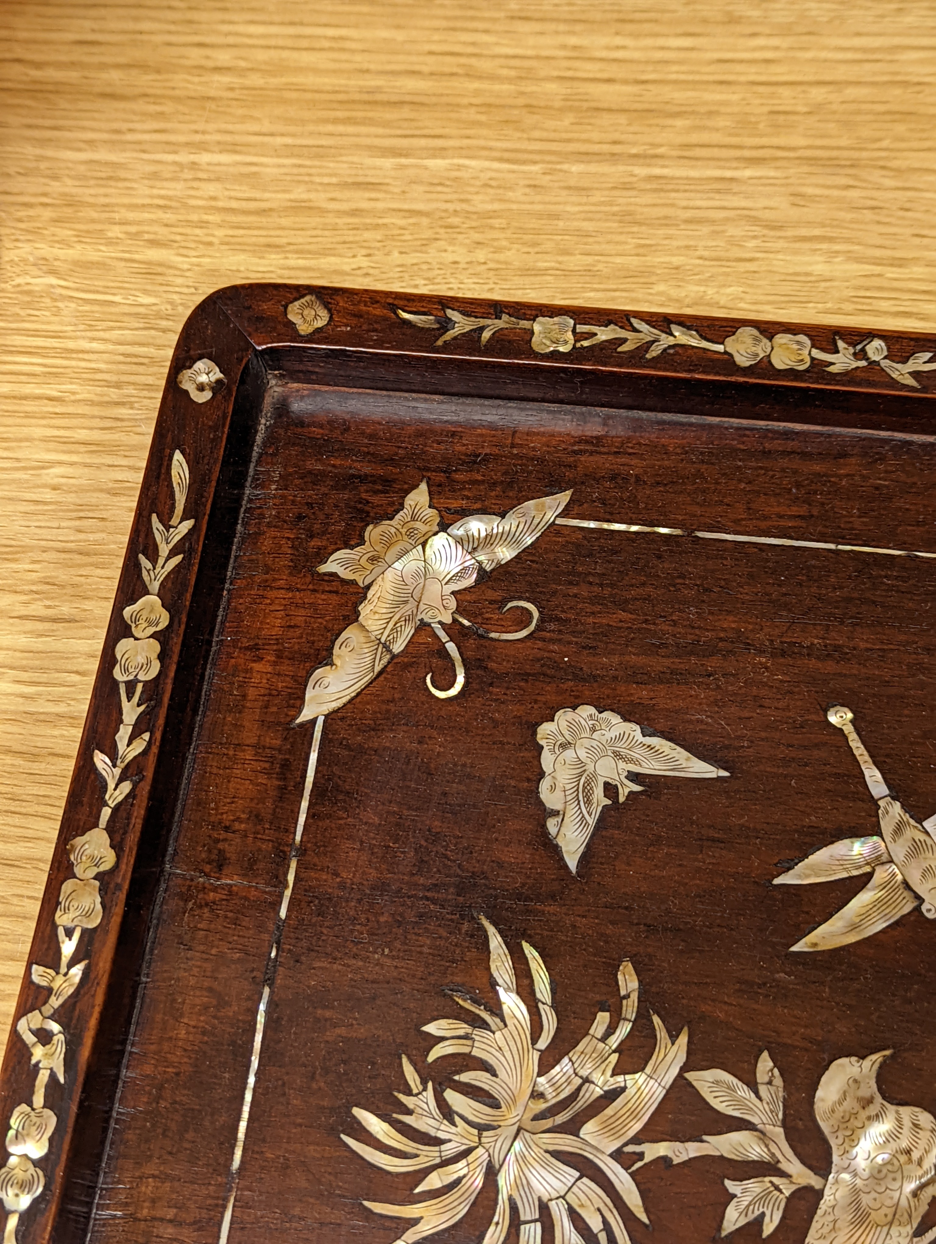 Two Chinese mother of pearl inlaid hongmu trays, the rectangular example with birds and insects amid flowers and the smaller oval example with a pavilion in a landscape within floral sprays 55x34cm